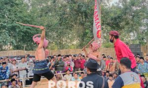 Momen saat dua pertarung Ojhung mengayunkan rotan di atas kepala.