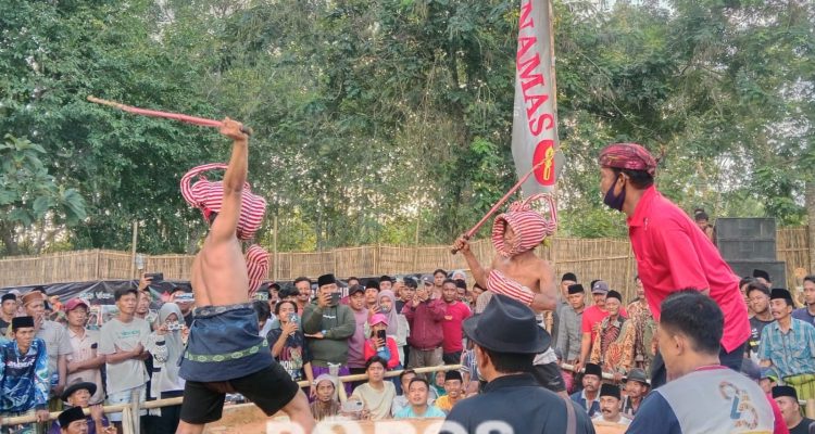 Momen saat dua pertarung Ojhung mengayunkan rotan di atas kepala.