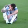 Leonel Messi Lionel Messi duduk di lapangan rumput dengan kepala menunduk sambil memegang wajahnya.